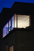 Zeitgenössisches Wohnhaus mit beleuchtetem Fenster in Nachtstimmung