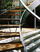 Curved staircase in courtyard with stainless steel stringer and wooden treads