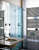 Kleines Designerbad mit Waschtisch neben Duschabtrennung aus Glas und Handtuchtrockner aus Edelstahl