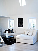 Bright living room with white corner sofa and black side table