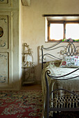 Metal bed with patterned cushions in bedroom with oriental carpet