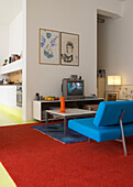 Wohnzimmer mit blauem Sofa und Teppichen in Rot und Blau