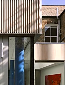Ausschnitt einer modernen Wohnhausecke mit blau getönten Rundstützen hinter Fenster
