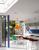 Bar stools in front of free-standing kitchen island and dining area in front of open terrace doors