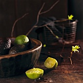 Limes and avocado in a wooden bowl