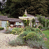 Garten mit Terasse, Lavendel und Sonnenschirm vor ländlichem Anwesen