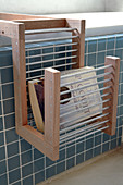 Rack made of wood and metal rods on blue-tiled bathtub