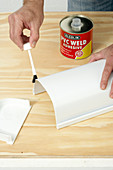 Painting the edge of a white plastic container with glue