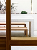 View of terrace with table and benches through window
