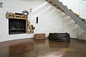 Rounded wall with open fireplace and polished concrete floor beneath staircase with curved steel stringer