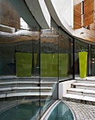 Terrace of contemporary house - reflections in curved glass facade and elliptical glass panel to light cellar