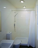 Compact configuration in a small space - cream tiles and white, modern bathroom furnishings with maritime ceiling lights