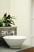 Wash basin with wall-mounted taps and integrated planter with flowering zantedeschia