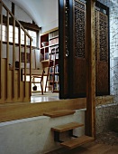 Schiebewände aus antiken geschnitzten Holzelementen vor Bibliothek und filigrane Drahtskulptur als transparente Trennwand