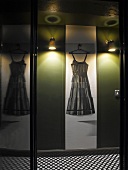 Reflections above black and white polka dot floor - dress on hanger between wall lights