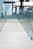 Staircase with glass balustrade on suspended steel girder and view of dining area