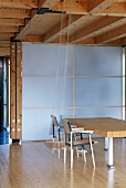 Dining area with solid table top in front of translucent partition in modern wooden house