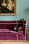 Painting above velvet sofa with dog in a room with a historical feel