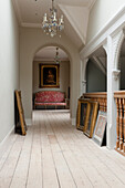 Hallway with chandeliers, paintings and floorboards in a historic house
