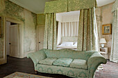 Four-poster bed and chaise longue in bedroom with historic wall design