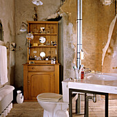 Rustic bathroom with exposed plaster and wooden cupboard