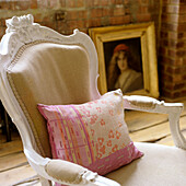 Baroque armchair with patterned cushion in front of brick wall