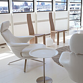 Modern lounge setting with white armchairs and wooden furniture in front of window front