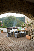 Terrasse mit Natursteinbogen, Pflanzkübeln und Marmortisch