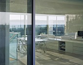 View of living space with sofa, shelves & dining table through large windows