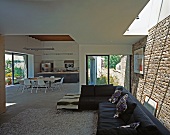 View from living room with black sofa into kitchen-dining area of contemporary house