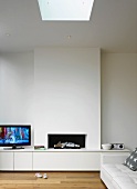 A modern fireplace with an integrated sideboard in a pure white room