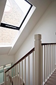 A stair way in an attic with a large skylight