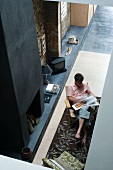 View from above of man sitting in armchair in front of fireplace