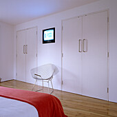 Minimalist bedroom with steel chair and red bedspread