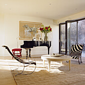 Modern living room with grand piano, armchairs with zebra pattern and floral arrangement