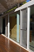 Überdachte Holzterrasse vor Wohnhaus mit Glasfassade