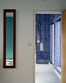 Foyer with open door and view of shower cubicle with blue mosaic tiles in bathroom