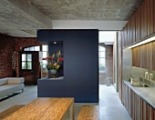 Offenes Wohnen in ausgebautem Fabrikraum mit blau getöntem Raumteiler