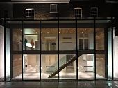 Zeitgenössischer Anbau mit Glasfront und Blick in beleuchteten mehrstöckigen Treppenraum