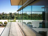 Umlaufende Terrasse vor Glasfassade eines zeitgenössischen Wohnhauses und Blick in Garten