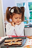 A little girl in front of a baking tray of gingerbread men