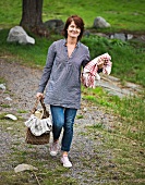 A woman carrying a picnic basket and a blanket