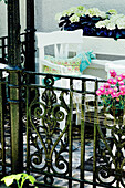 Patterned cushion cover on white garden chair behind wrought iron fence