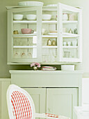 Country-style display cabinet with crockery and decoration in pastel colors
