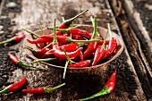 A wooden bowl of red chilli peppers