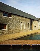 Renoviertes Bauernhaus mit Natursteinfassade und wasser gefülltes Becken