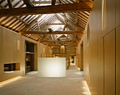 Designer-style, open-plan room in converted house with view of rustic roof timbers