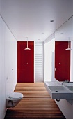 Narrow designer bathroom with wooden floorboards and red glass wall