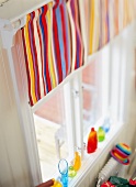 Colourful striped curtain on window, colourful vases on windowsill