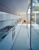 Schmaler langgestreckter Raum mit eingebauter Küche vor Fensterfront